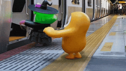 a yellow cartoon character is standing next to a green cartoon character in a witch costume