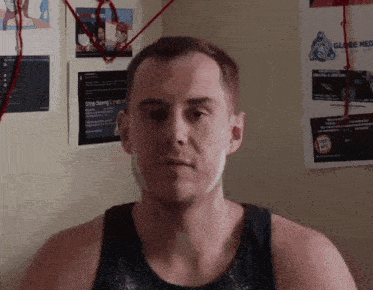 a man is standing in front of a wall with posters on it including one that says stop saying i 'm a