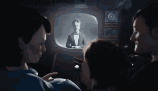 a group of people are watching a cartoon of an alien on a television screen