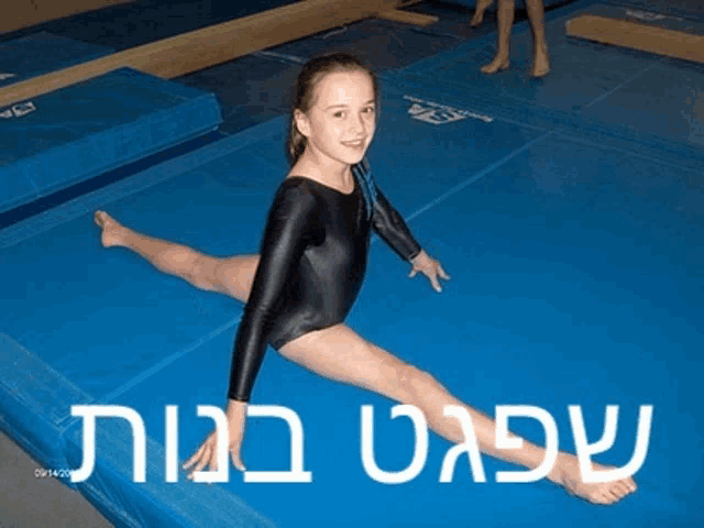 a girl in a black leotard is doing a split on a blue mat in hebrew