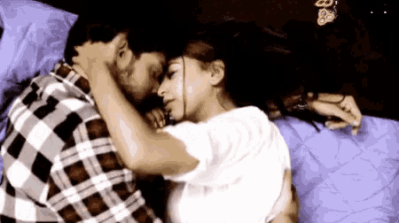 a man and a woman are laying on a bed kissing .