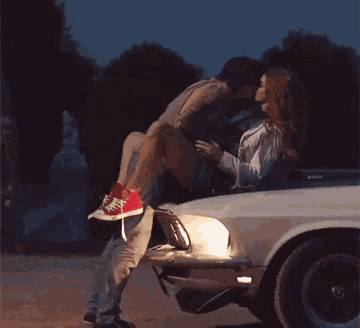 a man is carrying a woman in his arms in the back of a white car