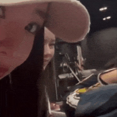 a woman wearing a hat is looking at the camera while another woman looks on .