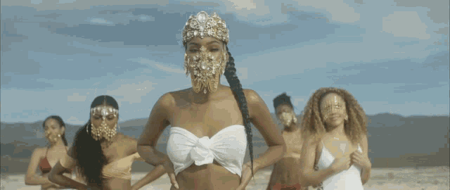 a group of women in bikinis are standing on a beach