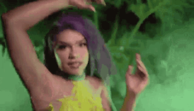 a woman with purple hair is dancing in a green room .