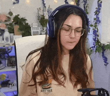 a woman wearing headphones and glasses is sitting in front of a monitor .