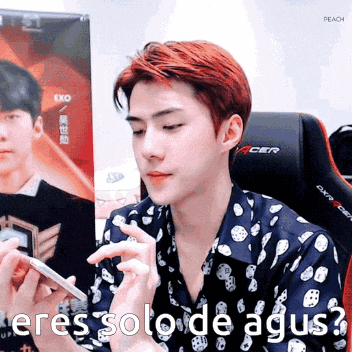 a man in a polka dot shirt is holding a cell phone and asking where solode agus