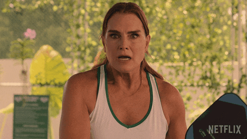 a woman in a white tank top is holding a blue netflix sign