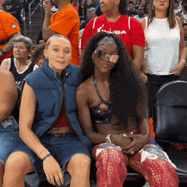 a woman wearing a red nba shirt sits in the stands