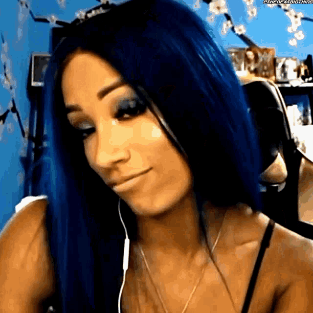a woman with blue hair is wearing headphones and a bra .