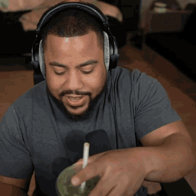 a man wearing headphones is pouring a drink into a cup with a straw