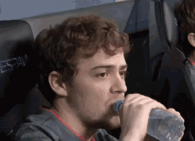 a man drinking water from a plastic bottle with the word espam on the back
