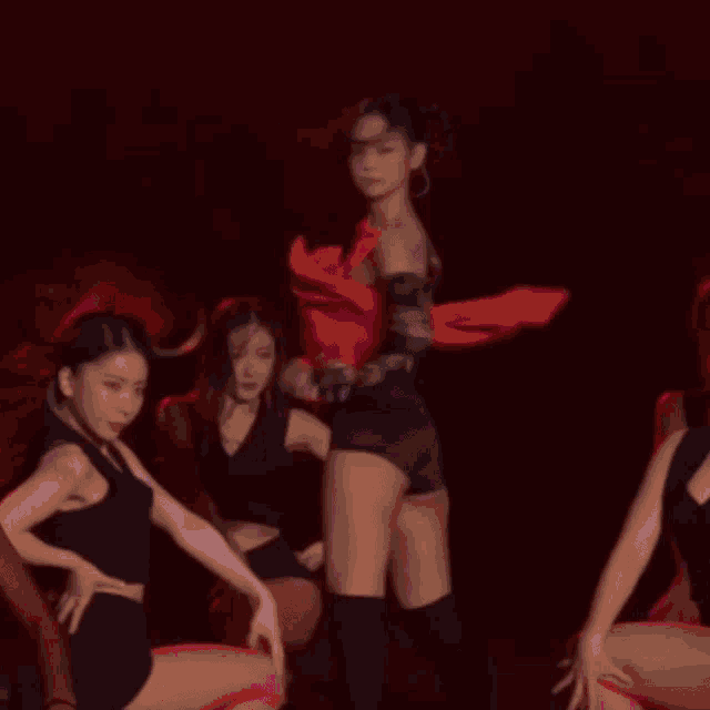 a group of women are dancing on a stage in front of a red background .