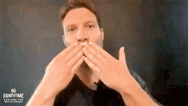 a man is covering his mouth with his hands while looking at the camera .