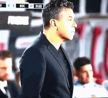 a man in a suit is standing in front of a scoreboard that says ' fox ' on it