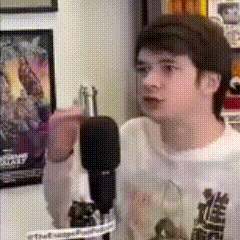 a young man is standing in front of a microphone while wearing a back to the future t-shirt .