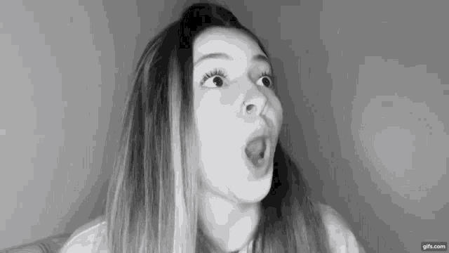 a black and white photo of a woman making a funny face .