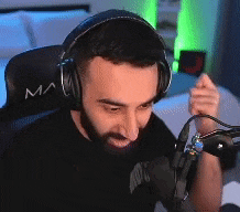 a man wearing headphones is sitting in front of a microphone and making a funny face .