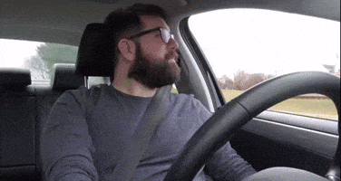 a man with a beard is driving a car