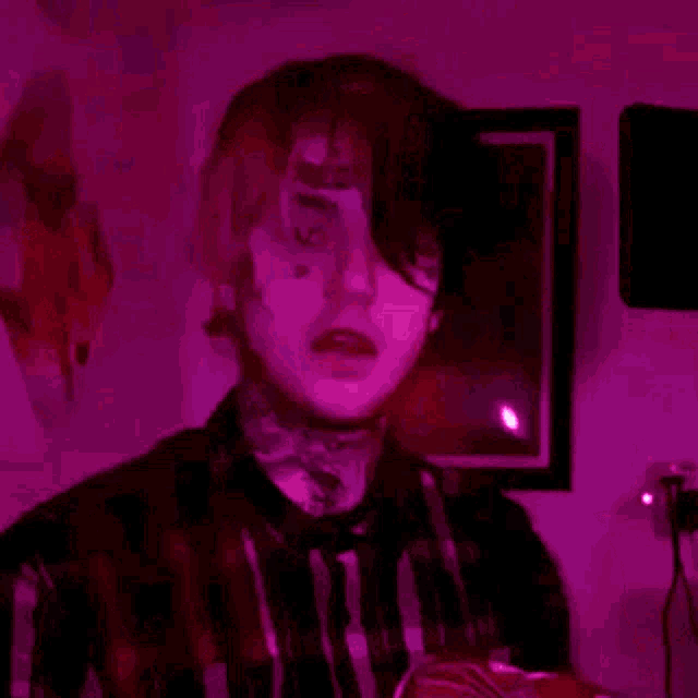 a young man with a tattoo on his face is holding a red object in his hands .