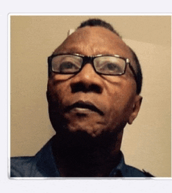 a man wearing glasses and a blue shirt looks up at the camera