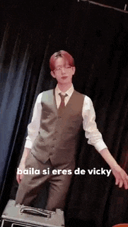 a man in a suit and tie is dancing in front of a black curtain .