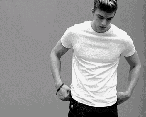 a man in a white t-shirt is adjusting his pants