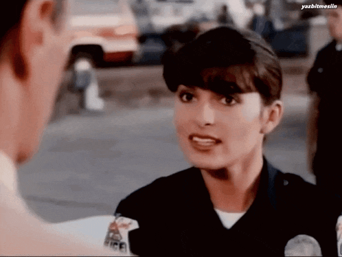 a woman in a police uniform talks to a man in a car