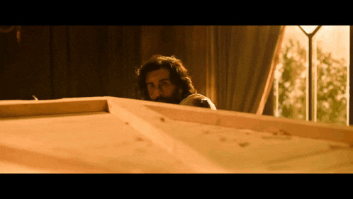 a man with a beard looks over a wooden box
