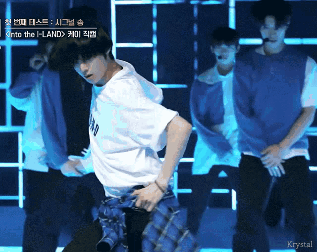 a group of young men are dancing on a stage with the words into the i-land on the bottom