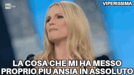 a woman with blonde hair is sitting in front of a blue background and says la cosa che mi ha messo