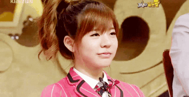 a girl with a ponytail is wearing a pink jacket and white shirt