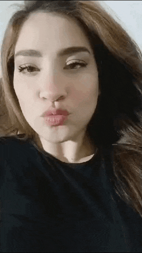 a close up of a woman making a kiss with her mouth open .