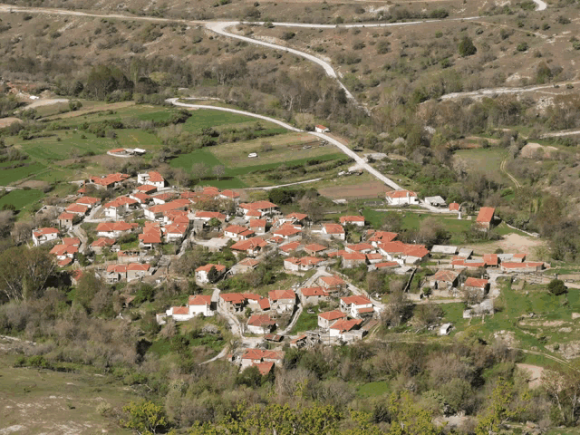 an aerial view of a small village surrounded by trees and grass