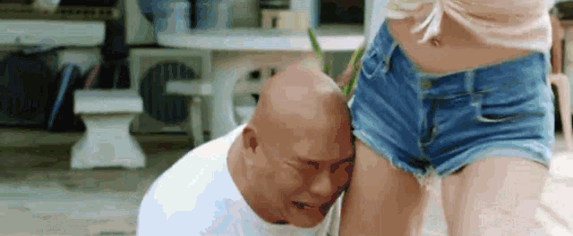 a bald man is crying next to a woman in shorts .