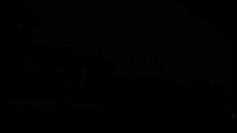 a train is going down the tracks at night with a sign on the side of it .