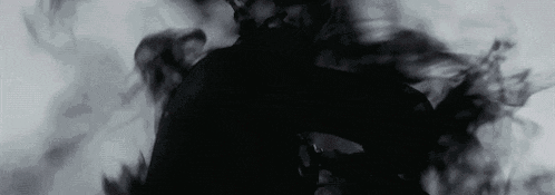 a person is standing in a dark room with smoke coming out of it .