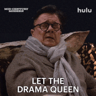 a man with glasses and a scarf is sitting on a couch and says let the drama queen