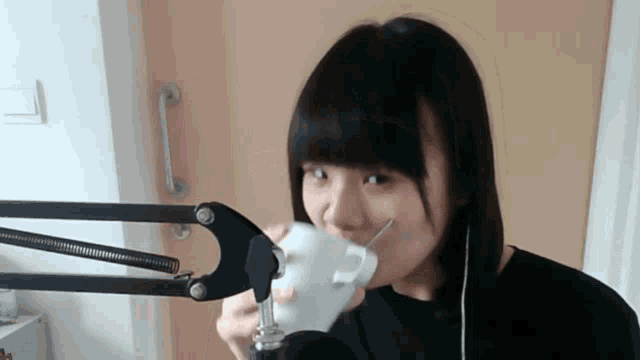 a girl drinking from a white cup with a straw