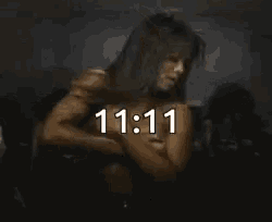 a naked woman is dancing in a dark room with the time 11:11 on the bottom .