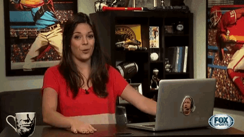 a woman sitting at a desk with a laptop and a fox sports logo on it