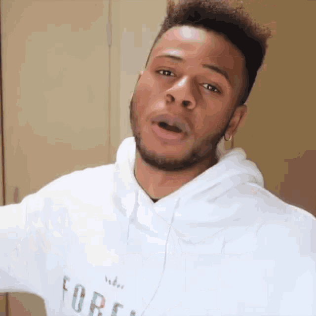 a man with a beard wearing a white hoodie with the word forever on it