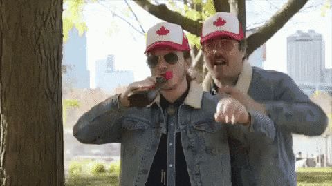 two men wearing hats with a maple leaf on them drinking from a bottle