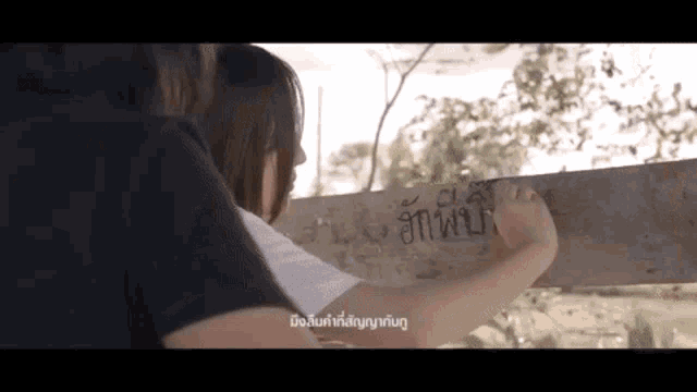 a woman is writing on a wooden board with a foreign language