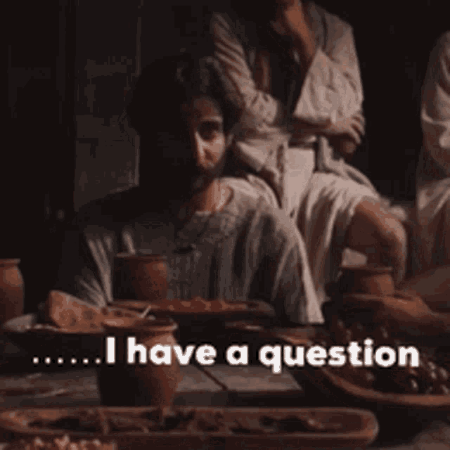 a man sitting at a table with the words i have a question written below him