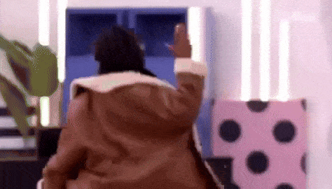 a person in a brown coat is standing in a room with polka dot furniture .