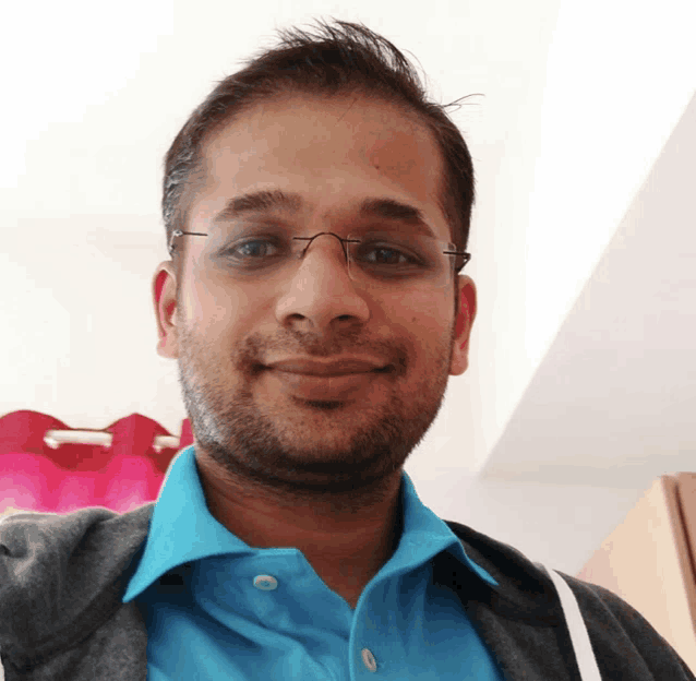 a man with glasses and a blue shirt smiles for the camera
