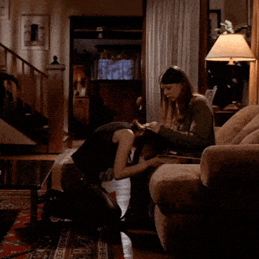 two women are kneeling down in a living room and one has her head on the other 's knee
