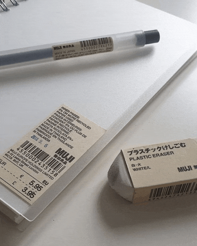 a muji plastic eraser sits next to a notebook