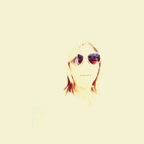 a woman wearing sunglasses looks at the camera with a white background